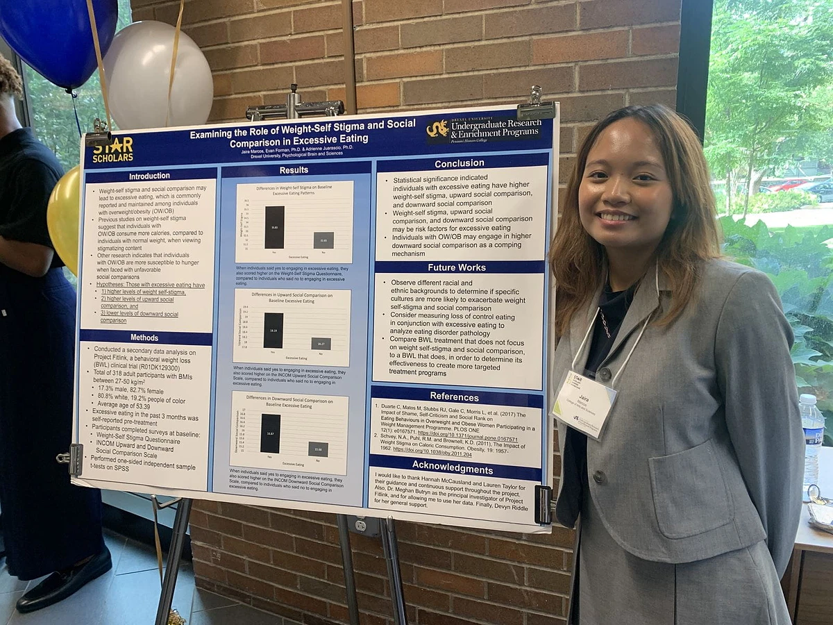 Jaira Marcos, psychology '26, standing with research poster