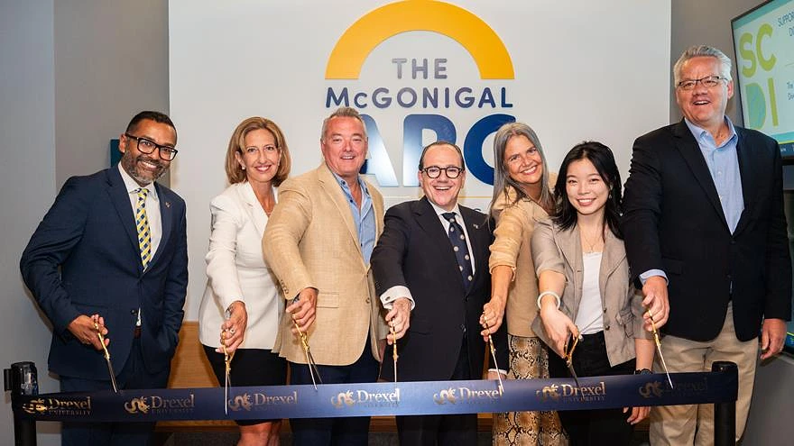 A group of people pose with scissors in front of a ribbon at the opening of The McGonigal Lab, associated with Drexel University.