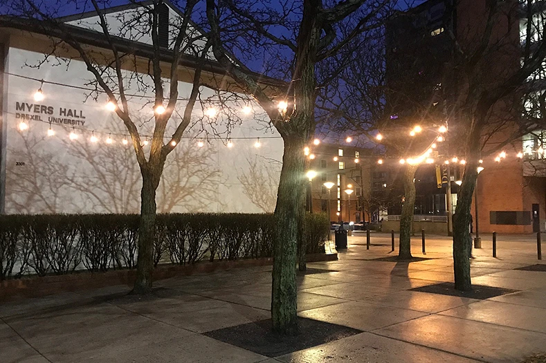 Sidewalk and white building at night with a string of lights